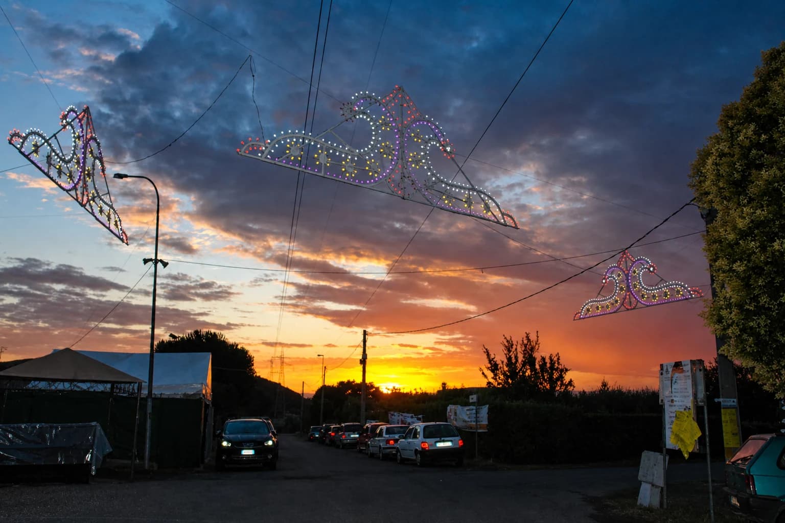 Le luminarie della Festa di Prato Rinaldo sospese sulla strada al tramonto nel 2014.
